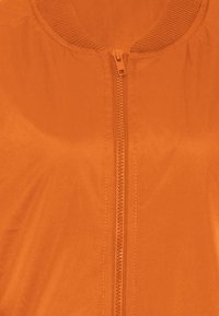 Oranje lichtgewicht jack met een ritssluiting en een geribbelde halslijn. Glasheldere textuur, geen patronen, effen kleurontwerp.