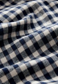 A pamut anyag kék és fehér kockás mintával rendelkezik, különböző méretű négyzetekkel, lágy textúrával és finom szövési részletekkel.