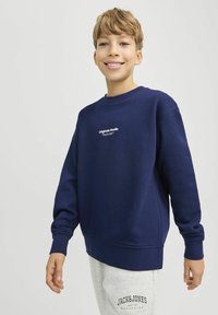 Sötétkék pulóver kerek nyakkal, bordás mandzsettával és fehér szöveges logóval a mellrészen. Lazákré design, kényelmes fazon.