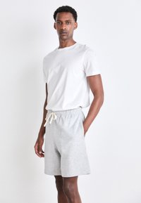 Gray cotton shorts with an elastic waistband and drawstring, paired with a plain white short-sleeve t-shirt. Simple, casual design.