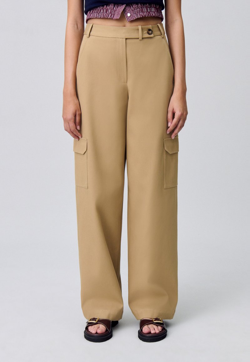 Pantaloni cargo beige a gamba larga con due tasche laterali, chiusura con bottone e passanti per la cintura, realizzati in un tessuto morbido.