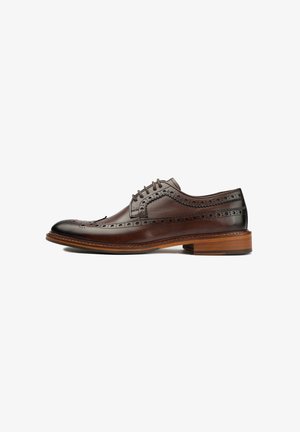 Brown leather oxford shoe featuring brogue detailing, a rounded toe, and a contrasting wooden heel. Smooth texture with subtle shine.