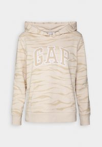 Beige ja kerma raidallinen huppari, jossa etutasku ja suuri "GAP"-logo kerma- ja valkoisella tekstillä rinnassa.