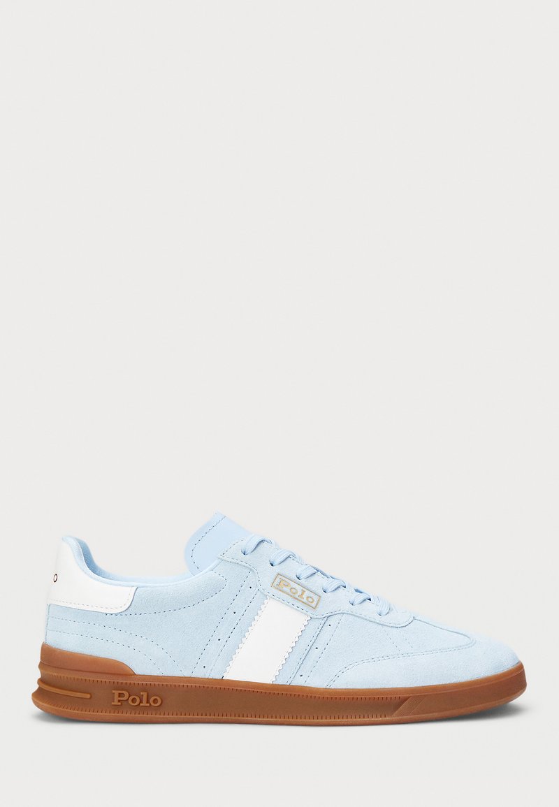 Hele sinine sametist sneaker valge triibuga, kummist tallaga ja logodetailiga. Lame pael ja pehmendatud keel suurendavad mugavust.