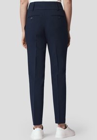 Granatowe spodnie o dopasowanym kroju, wykonane z gładkiego materiału, z dwoma tylnymi kieszeniami zapinanymi na guziki i czystym wykończeniem pasa.