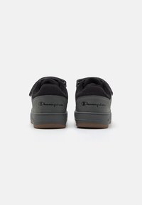 Sneaker nere Champion con tomaia in maglia testurizzata, tallone imbottito e cinturini in velcro; suola in gomma con logo sul retro.