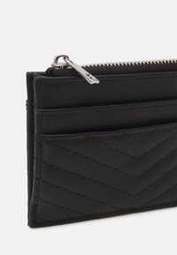 Schwarzes Leder-Kartenetui mit einem gesteppten Chevron-Muster, ausgestattet mit mehreren Kartenfächern und einem silbernen Reißverschluss.