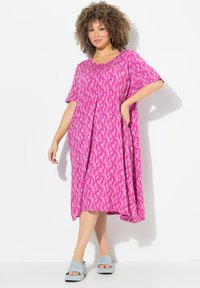 Abito rosa con motivi, maniche corte, pieghe e vestibilità ampia. Abbinato a sandali platform azzurri chiari. Tessuto dalla texture morbida.