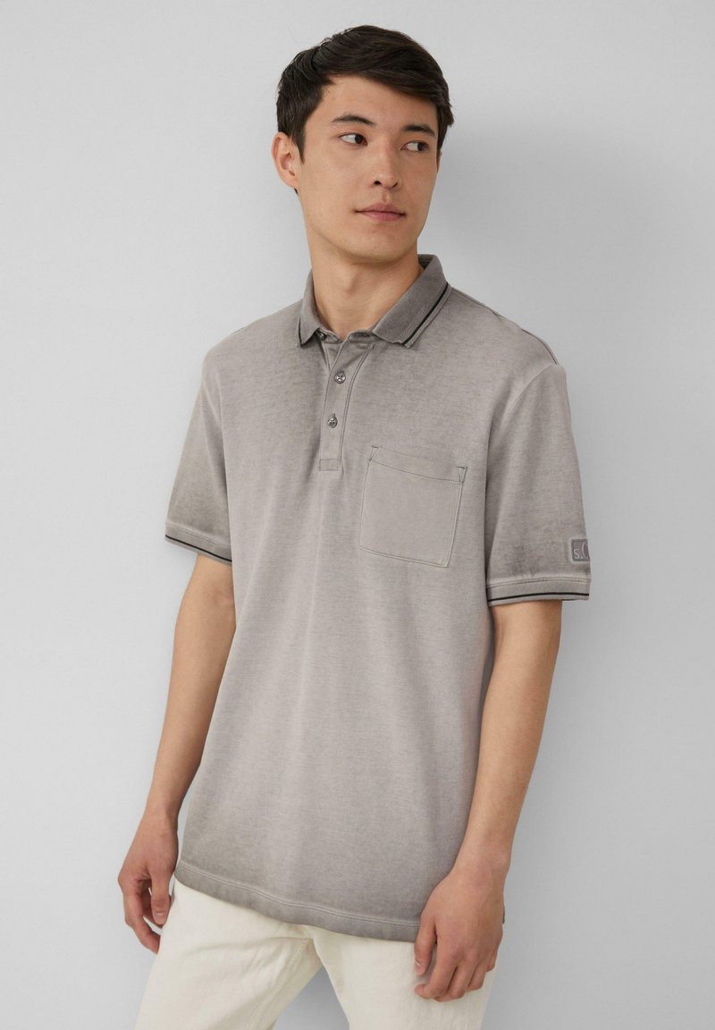 Grijze polo shirt met een kraag, drie knopen en een borstzakje. Heeft contrasterende donkere biezen op de kraag en de mouwen.