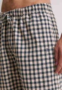 Pantalones cortos de algodón a cuadros en verde oscuro, crema y rojo, con una cintura elástica y un pequeño logo bordado en el costado.