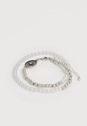 Dubbel rij armband met afwisselend witte parels en zilveren kralen, met een zilveren ovale bedel met een sterontwerp en een karabijnsluiting.