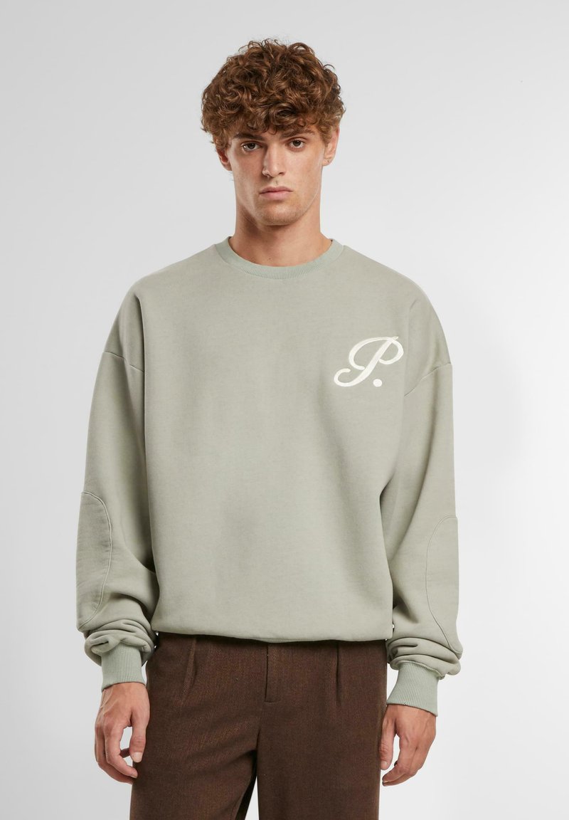 Lys grønn sweatshirt med rund hals og løs passform. Har en liten hvit logo på brystet og ribbestrikkede mansjetter. Myk stofftekstur.