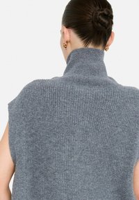 Maglione grigio a collo alto senza maniche in maglia, con texture a costine, caratterizzato da un colletto alto e spalle scoperte per un fit rilassato.