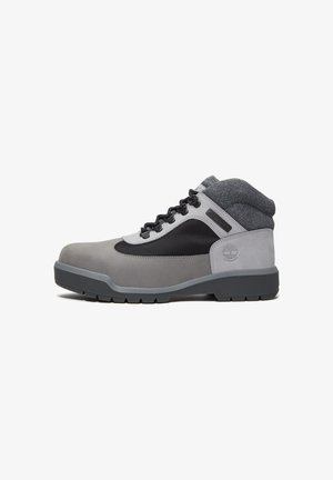 Gray and black waterproof hiking boot with padded ankle collar, black laces, and durable treaded sole, side view on white background.