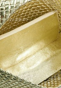 Gouden pouch met een gladde, glanzende textuur en ritsluiting. Het interieur heeft geweven gouden accenten, wat de algehele metalen uitstraling versterkt.