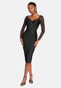 Schwarzes, tailliertes Kleid mit langen Spitzenärmeln, strukturiertem Oberteil und knie-langer Saum. Transparente Spitze und eine strukturierte Stoffoberfläche.