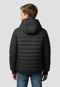 Sort dunjakke med hætte, med quiltet design og ribstrikkede manchetter. Bruges over et par blå jeans, som viser en tekstureret stof.