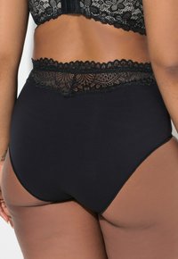 Zwarte high-waisted panties met een kanten tailleband detail. Glad stofoppervlak met ronde snijdetails, versierd met een ingewikkeld kantpatroon.