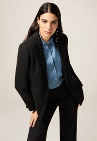 Czarna marynarka w prążki na jasnoniebieską koszulę, o g�ładkiej fakturze i dopasowanym kroju, z dopasowanymi, skrojonymi spodniami.