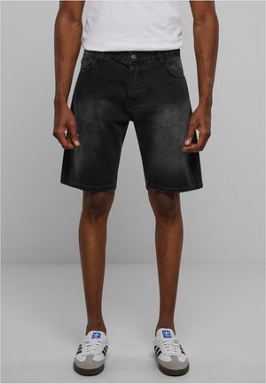 Zwarte denim shorts met een lichte vervaging, vijfzakken ontwerp en riemlussen, gecombineerd met witte en grijze sneakers met zwarte strepen.