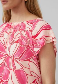 Bloes met bloemenprint in een roze en crèmekleurig palet, geplooid ontwerp en korte mouwen van zachte, lichte stof.