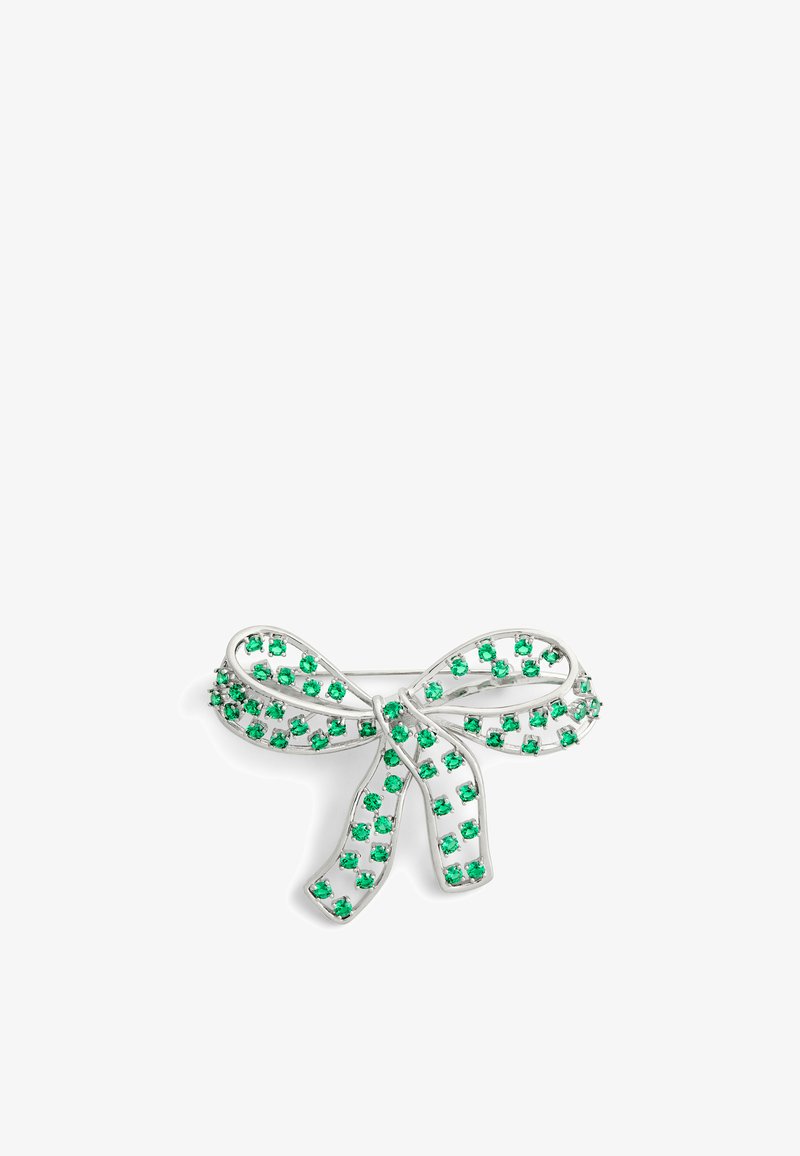 Broche en forme de courbe argentée ornée de strass verts, disposée dans un design en filigrane, avec une finition texturée et un système de fermeture par épingle traditionnel.