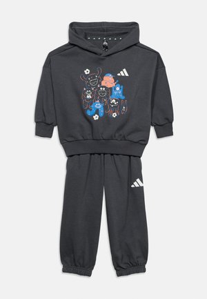 Σετ παιδικής φόρμας με φούτερ και παντελόνι σε ανθρακί γκρι, με πολύχρωμο σχέδιο καρτούν τέρατα στο μπροστινό μέρος και λευκό λογότυπο στο φούτερ και το παντελόνι.