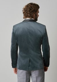 Sacou din catifea de culoare teal închis, cu guler din satin negru, croială slim fit și mâneci lungi. Prezintă o textură subtilă și un design croit.