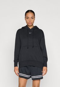 Μαύρο hoodie με κορδόνια, που διαθέτει λευκό λογότυπο Nike στο στήθος. Συνδυάζεται με σκούρες βερμούδες που έχουν λευκές ρίγες στην άκρη.