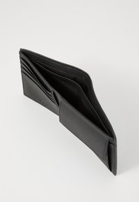 Svart lærpung med flere spor for kort, en teksturert overflate og en fold-over lukking. Innvendig har den en glatt fôr.