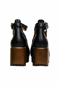 Zwarte leren hoge hakken met een bruine blokhak, voorzien van een enkelbandje en een afgerond achterkantontwerp.