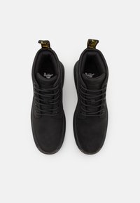 Botas de cuero negro con puntera redonda, diseño de cordones, cuello acolchado y tirador amarillo. Textura suave y detalles en los laterales.