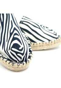 Espadrilles à motif zèbre avec un tissu texturé noir et blanc, bout rond et semelle en jute naturel avec bords cousus.