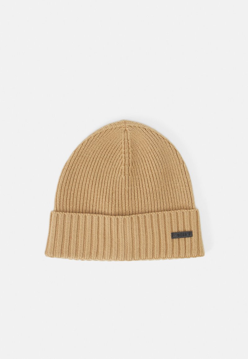 Wool knit beanie in camel color with a ribbed texture, featuring a folded cuff and a small black label on the side.