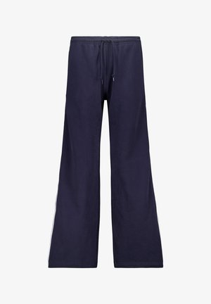 Pantalones de chándal de color navy con cintura elástica y cordón, diseño de pierna ancha y franjas blancas en contraste a lo largo de las costuras laterales. Textura de algodón suave.