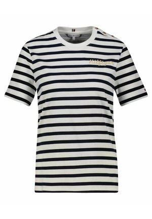 Chemise blanche à manches courtes avec des rayures horizontales noires, écriture dorée "Hilfiger" sur la poitrine, et trois boutons dorés sur l'épaule gauche.