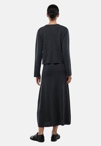 Ensemble en tricot gris foncé comprenant un haut à manches longues court et une jupe longue. Le tissu semble doux avec une texture subtile.