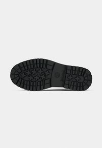 Semelle de botte noire avec un motif de profil profond comportant des formes croisées et le logo Timberland au centre.