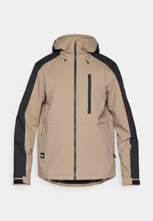 Beige og svart hettegenser med frontglidelås, vertikal brystlomme, sidelommer og justerbare mansjetter med borrelås.