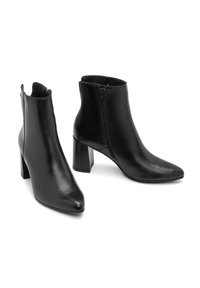 Mustat nahkaiset nilkkasaappaat, joissa on terävä kärki, sivuvetoketju ja lohkokorko. Sileä pinta ja minimalistinen muotoilu.