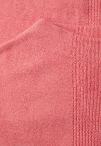 Vaaleanpunainen neulottu kangas, jossa on pehmeä tekstuuri; oikealla puolella resorikuvioinen osa ja vasemmalla sileä alue.