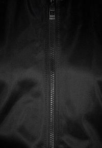 Černá bunda na zip s texturovanou, hladkou látkou. Zip je umístěn vertikálně a nahoře je malá štítek s logem značky.