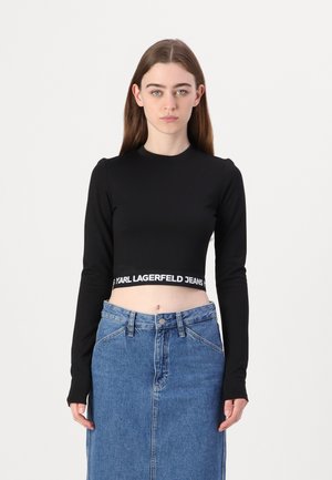 Black cropped long-sleeve top features a logoed waistband. Paired with a high-waisted denim skirt in a light blue wash.