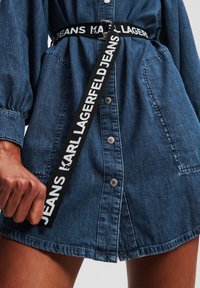 Traper haljina u tamnoplavoj boji, sa prednjim dugmadi, elastičnim puf rukavima i kontrastnim crnim remenom s natpisom "KARL LAGERFELD JEANS".