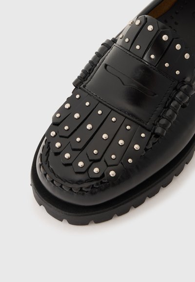 Schwarze Lederloafers mit einem gesteppten und fransigen Design im oberen Bereich, einer dicken Gummisohle und kontrastierenden glänzenden Akzenten.