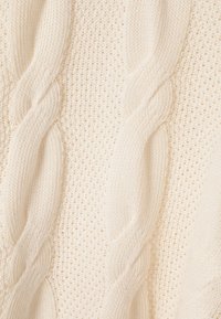 Kabeļu adījuma džemperis krēmkrāsā, ar teksturētām rakstām, atvērto un slēgto diegu sajaukumu, un mīkstu, biezu diegu.