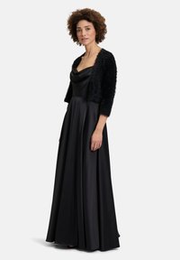Schwarz-satin Abendkleid mit Cowl-Ausschnitt und fließendem Rock, kombiniert mit einem flauschigen schwarzen Kurzcardigan. Elegantes und formelles Design.
