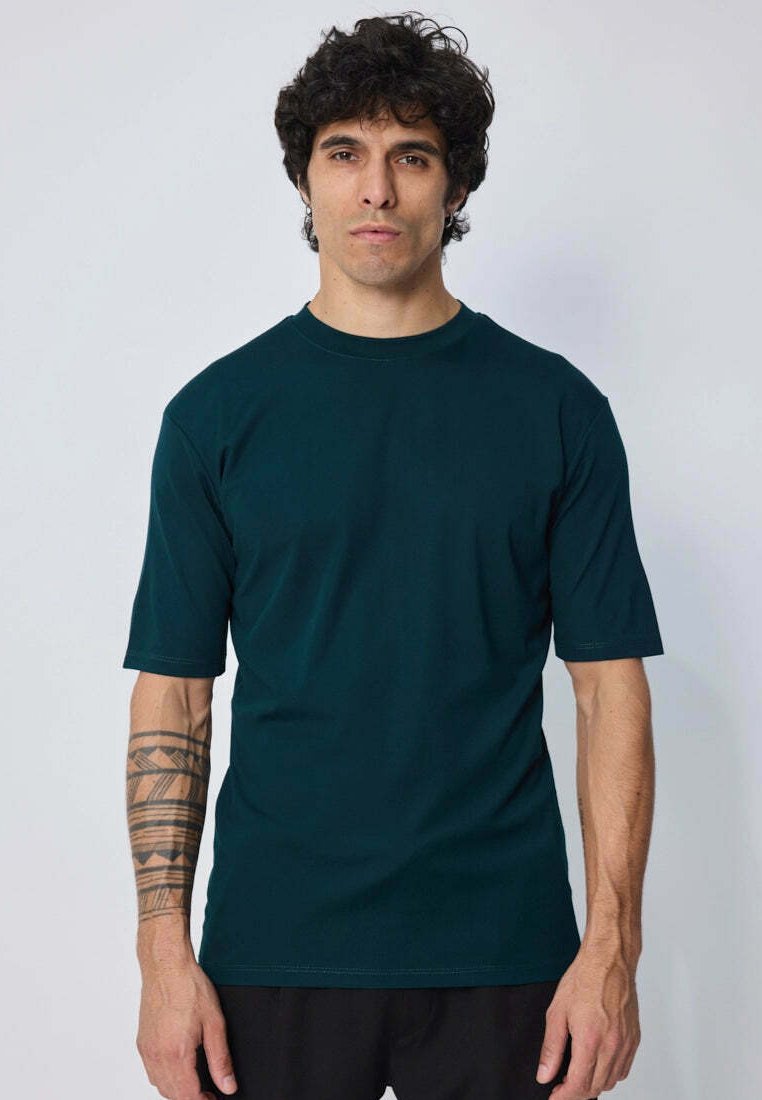T-shirt court à manches courtes de couleur vert foncé, fabriqué en tissu doux avec un col rond. Dispose d'une coupe décontractée et de coutures plates pour plus de confort.
