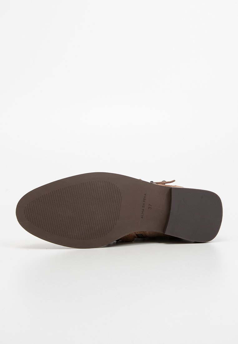 Scarpa in suede marrone con tomaia in tessuto, suola piatta in gomma e tacco basso. Presenta cuciture semplici e un marchio all'interno della suola.