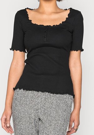 Top noir à côtes avec un col rond, des manches courtes et des bords froncés, comportant trois boutons sur le devant et une silhouette cintrée.